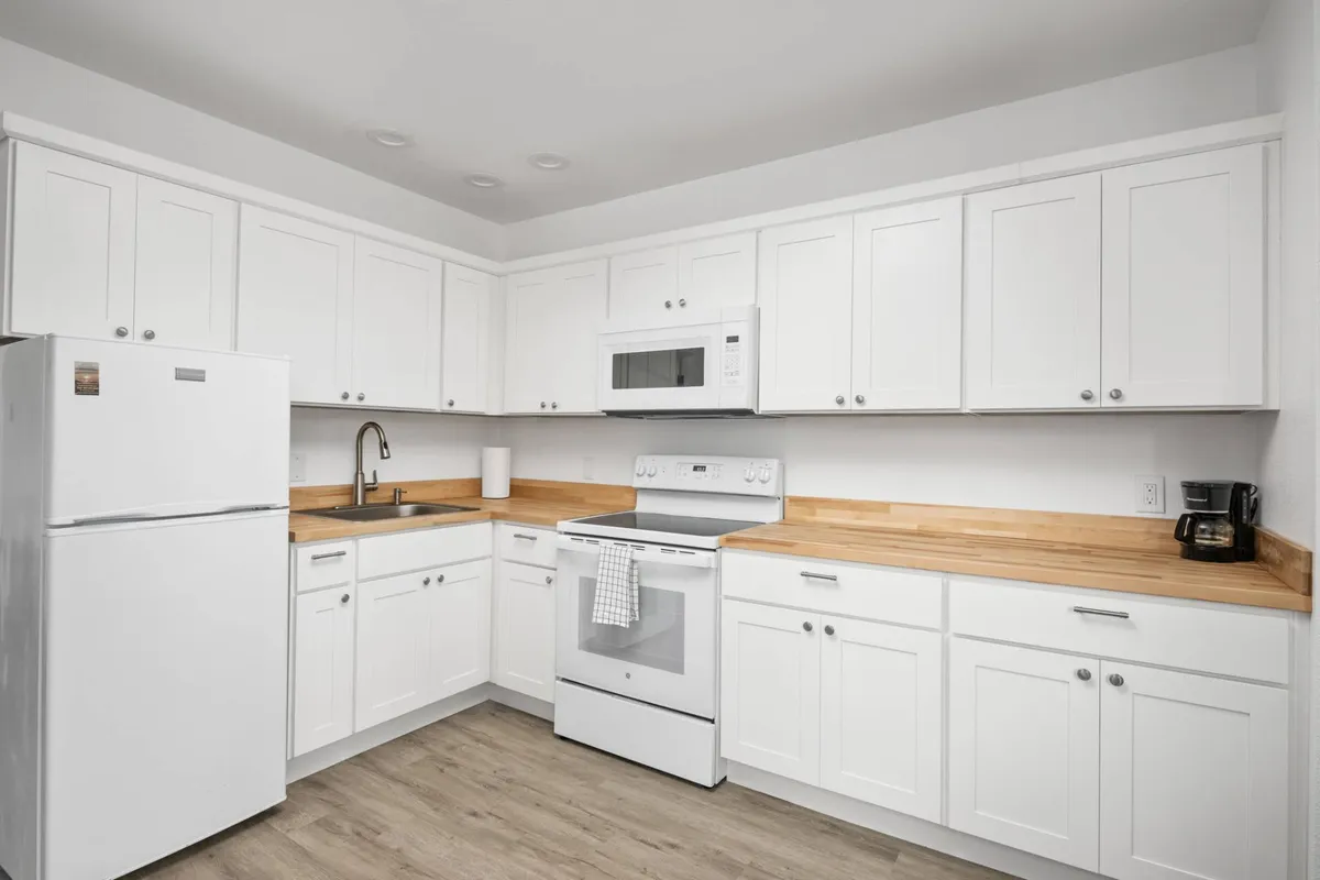 A well-appointed kitchen with white cabinetry, wooden countertops, and modern appliances. The space feels both welcoming and highly functional, ideal for preparing meals and gathering with loved ones.