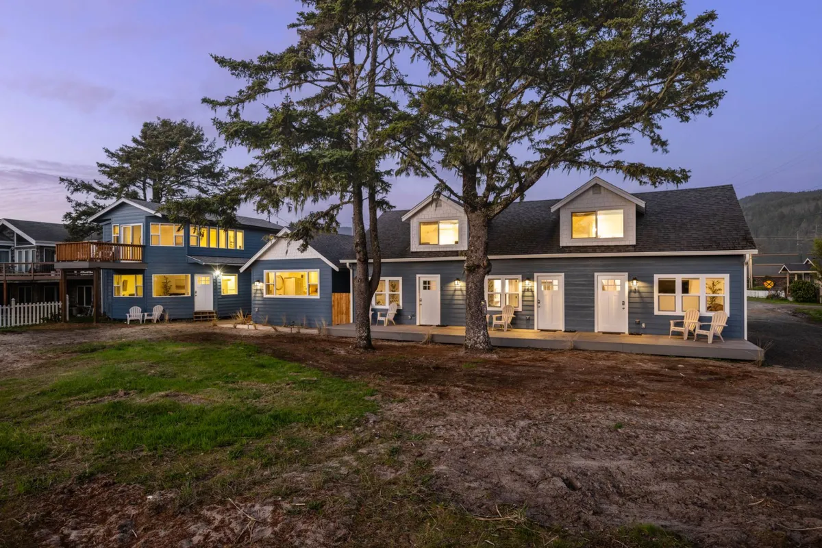 A warmly lit exterior shot of the main house and attached unit, framed by large trees and inviting outdoor seating. The space feels both private and communal, perfect for quiet moments or evening gatherings with family and friends. The setting sun adds a cozy, welcoming glow.