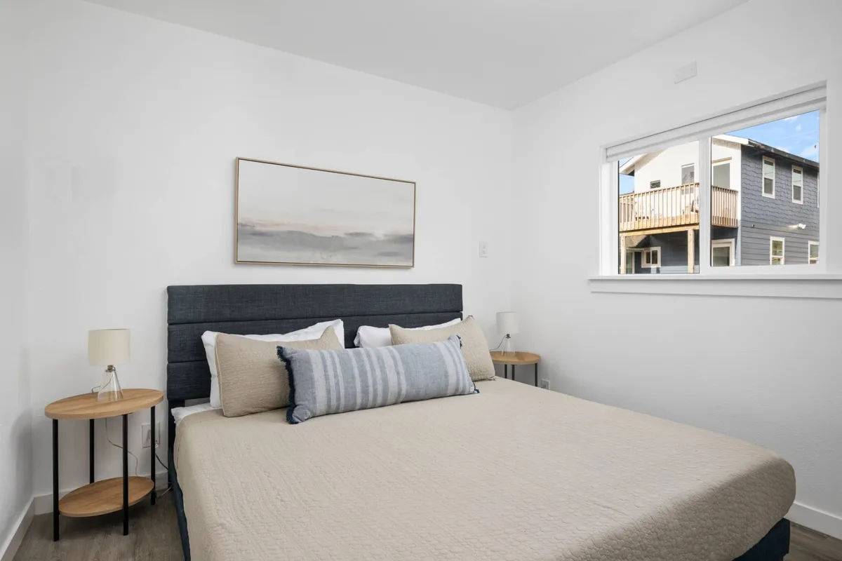 A serene bedroom with a king bed, accent artwork above the headboard, and a window letting in natural light. The room exudes tranquility and comfort, promising restful nights and peaceful mornings.